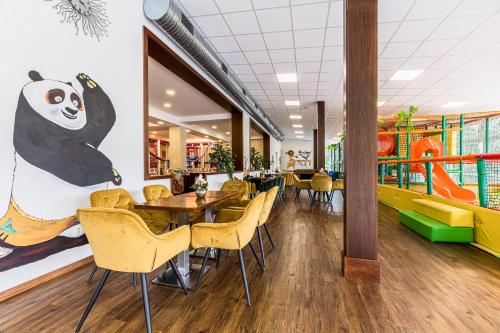 a restaurant with a panda mural on the wall and tables and chairs at Hotel Lesana in Vysoké Tatry