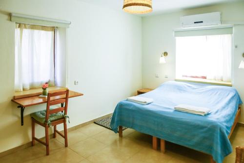 a bedroom with a bed and a desk and a window at Neot Semadar Eco Lodge in Naẖal Ya‘alon