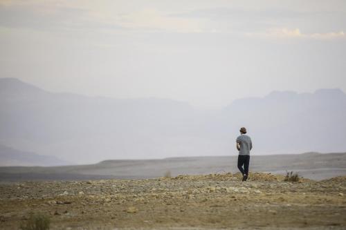 a man standing on a hill in a field at Neot Semadar Eco Lodge in Naẖal Ya‘alon