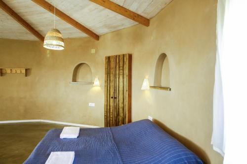 a bedroom with a blue bed and two windows at Neot Semadar Eco Lodge in Naẖal Ya‘alon