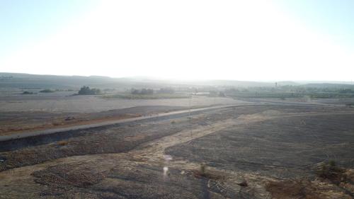 an empty field with a road in the distance at Neot Semadar Eco Lodge in Naẖal Ya‘alon