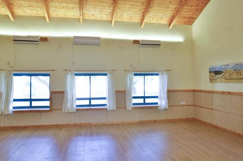 an empty room with three windows and a wooden floor at Neot Semadar Eco Lodge in Naẖal Ya‘alon