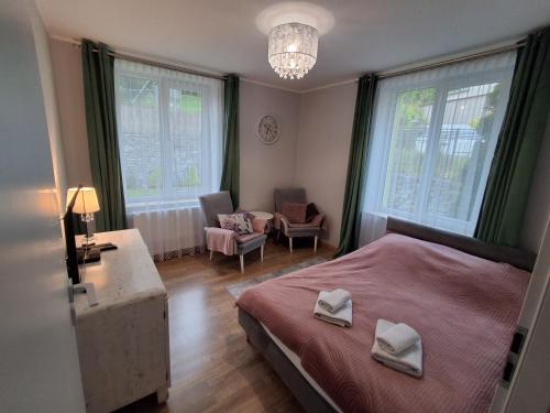 a bedroom with a bed and a chair and windows at Apartament JOANNA in Sanok