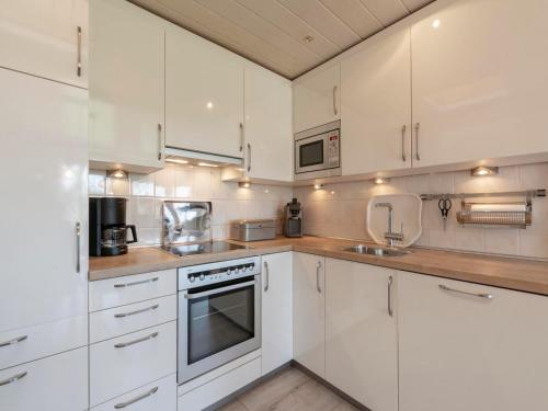 a white kitchen with white cabinets and appliances at Bungalow at Garnekuul park with garden in Callantsoog