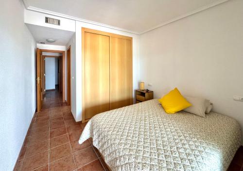 ein Schlafzimmer mit einem Bett mit einem gelben Kissen darauf in der Unterkunft Paraíso a Orillas del Mar Mediterráneo 40 in Villajoyosa