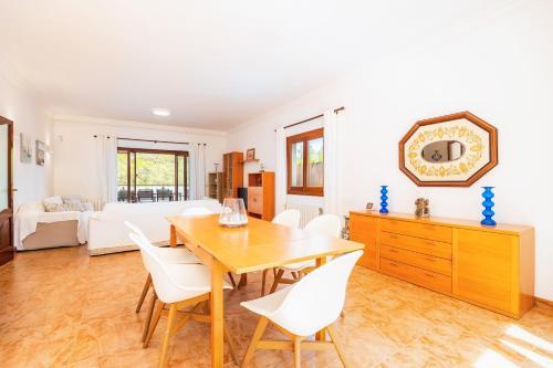 a dining room with a wooden table and white chairs at Tomymar in Cala Ratjada