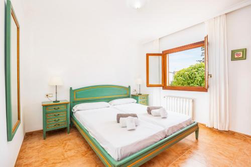 a bedroom with a green bed and a window at Tomymar in Cala Ratjada