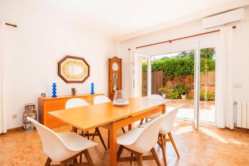 a dining room with a wooden table and white chairs at Tomymar in Cala Ratjada
