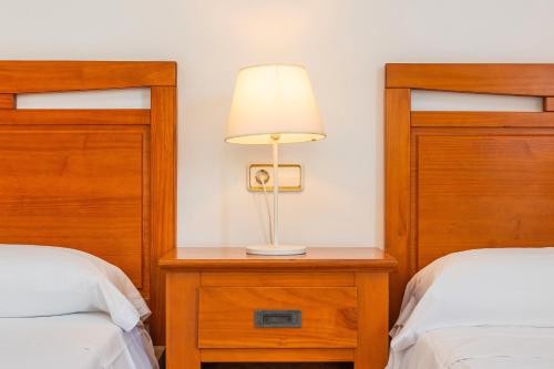 a bedroom with two beds and a lamp on a night stand at Tomymar in Cala Ratjada