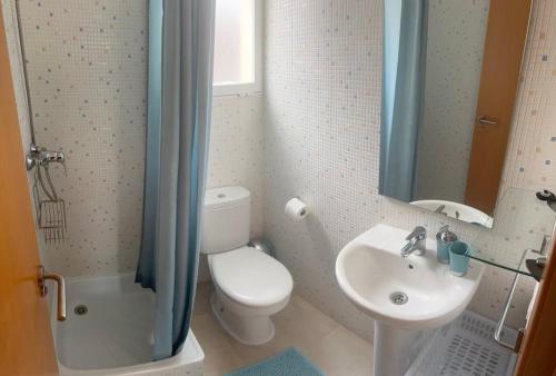 a bathroom with a toilet and a sink and a mirror at Chula Vista Apartamento, 200m de la playa, piscina, parking in Daimuz