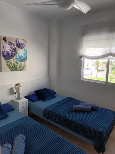 a bedroom with two beds and a window at Chula Vista Apartamento, 200m de la playa, piscina, parking in Daimuz
