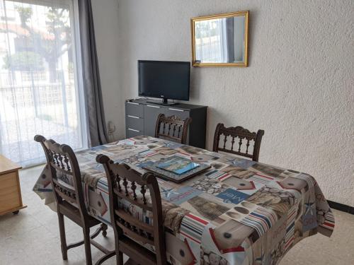 une table à manger avec des chaises et une télévision dans l'établissement T2 Climatisé, 2 Cours, Proche Plage, Parking Privé, 5 Pers., Animaux Acceptés - FR-1-797-58, à Port-la-Nouvelle