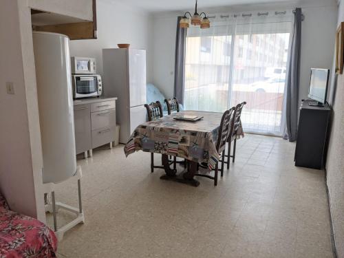 une salle à manger avec une table et des chaises et une cuisine dans l'établissement T2 Climatisé, 2 Cours, Proche Plage, Parking Privé, 5 Pers., Animaux Acceptés - FR-1-797-58, à Port-la-Nouvelle