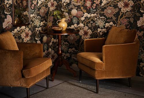 two chairs and a table in a room with floral wallpaper at Stay North - Matri House in Mathildedal