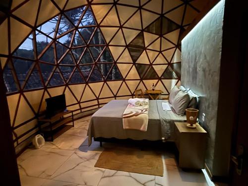 a room with a bed and a large window at Pousada Domos Serra do Sol in Monte Verde