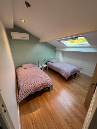 two beds in a room with a skylight at La petite Varenne 28 in La Chapelle-du-Noyer