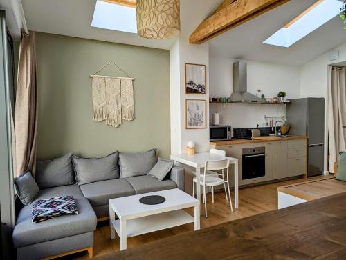 un salon avec un canapé et une cuisine dans l'établissement La Petite Roche, dépendance cosy avec sauna, à Indret