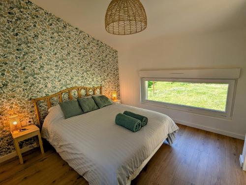 une chambre avec un lit avec des oreillers verts et une fenêtre dans l'établissement La Petite Roche, dépendance cosy avec sauna, à Indret