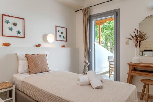 a white bedroom with a bed and a mirror at Agia Marina Apartments 7 Andros in Andros