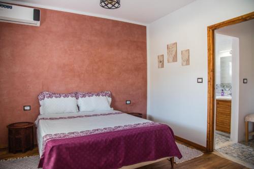 a bedroom with a bed with a purple blanket at Dar Lina "Charme et nature" in El Haouaria
