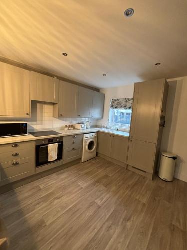 a kitchen with white cabinets and a washer and dryer at Central Lakes Staycation in Penrith