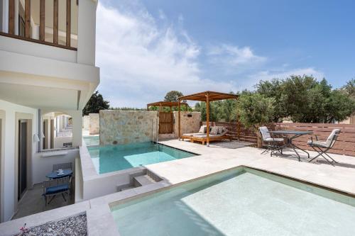 a swimming pool on a patio with a table and chairs at Aegean Houses in Kos Town