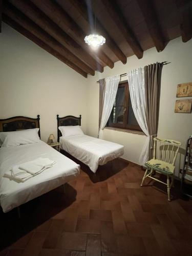 a bedroom with two beds and a window at Casale la COLLINA DEI CILIEGI in Acquapendente