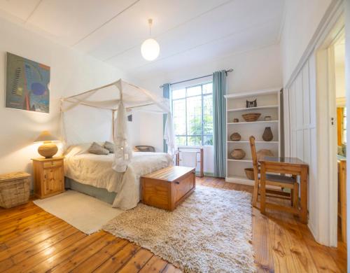 ein Schlafzimmer mit Himmelbett und Tisch in der Unterkunft Forest Haven in Harare
