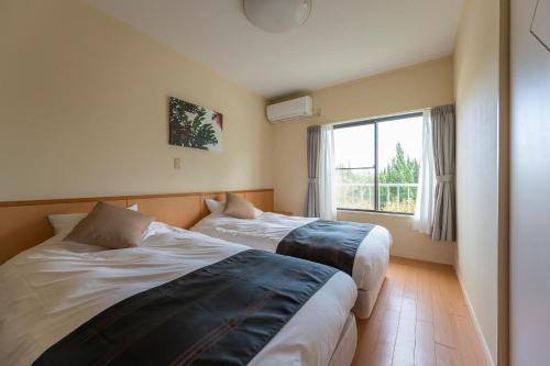 two beds in a room with a window at Le Nessa Jyogasaki in Ito