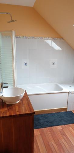 une salle de bain avec une baignoire blanche et un lavabo dans l'établissement ancienne grange, à Arçonnay