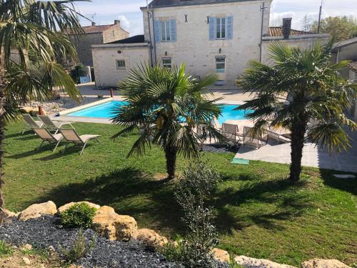 une piscine avec deux palmiers et une maison dans l'établissement Villa Meunière, à Le Bourdet