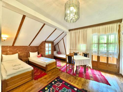 a bedroom with two beds and a table in it at Hotel Oka i Po in Berane