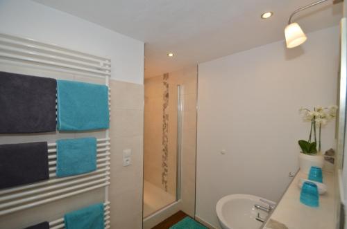 a bathroom with a sink and a shower with blue towels at Hotel Feiden Garni in Ediger-Eller