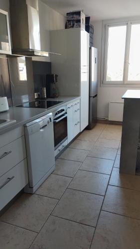 Il comprend une cuisine avec des appareils électroménagers blancs et du carrelage. dans l'établissement appartement le cézanne, à Toulon