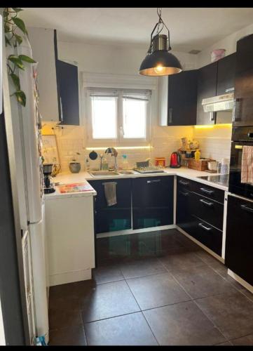 une cuisine avec des placards noirs et blancs et une fenêtre dans l'établissement Chambre proche circuit 4 personnes, au Mans