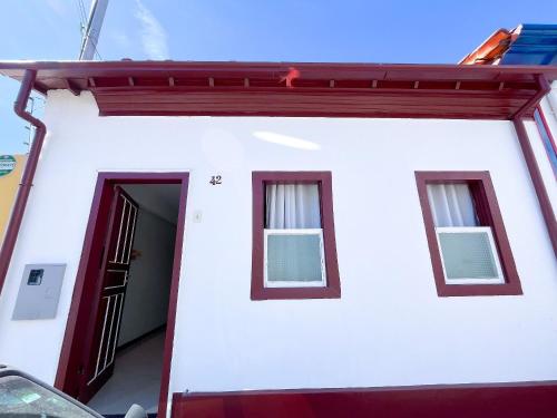 a white house with two windows and a door at Aconchego do Mercado Velho in Diamantina