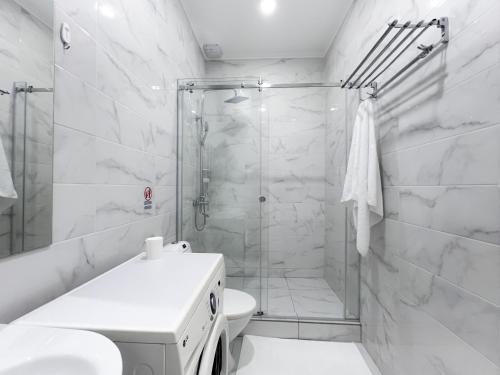 a white bathroom with a shower and a toilet at Raduga Orion villa in Chon-Sary-Oy