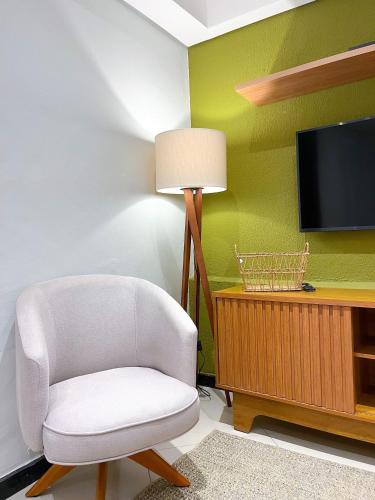 a living room with a white chair and a tv at Aconchego do Mercado Velho in Diamantina