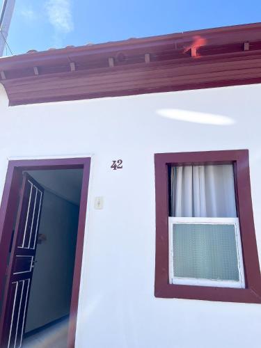 a window on a white building with a door at Aconchego do Mercado Velho in Diamantina