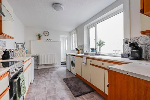 a kitchen with white counters and a large window at Flo Suite by Koya Homes-3-Bed Home-Parking in The Mumbles