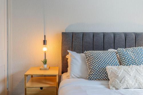 a bed with pillows and a table with a lamp at Flo Suite by Koya Homes-3-Bed Home-Parking in The Mumbles