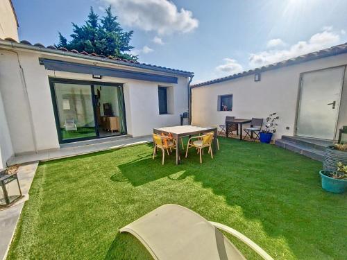 une pelouse avec une table et des chaises dans une cour dans l'établissement Rognac centre au calme maison entiere 5 couchages et jardin, à Rognac