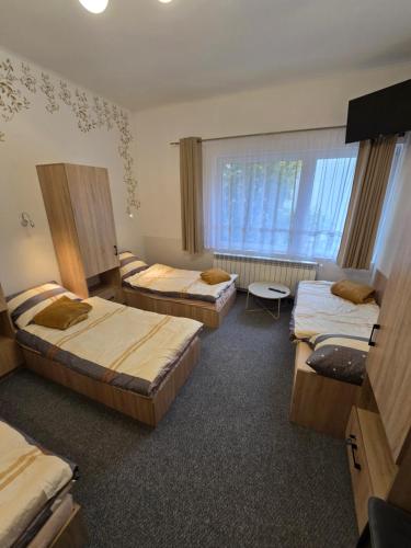 una stanza con tre letti e una finestra di Pokoje gościnne GOOD NIGHT apartamenty, noclegi a Będzin