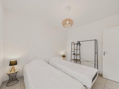 - une chambre blanche avec 2 lits et une lampe dans l'établissement Jolie maison pour 4 personnes avec jardin, à Saint-Vincent-sur-Jard