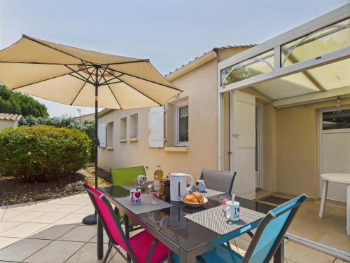 une table et des chaises avec un parasol sur une terrasse dans l'établissement Jolie maison pour 4 personnes avec jardin, à Saint-Vincent-sur-Jard