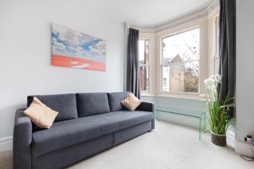 a living room with a blue couch and a window at 1 bed Clapham Junction apartment in London