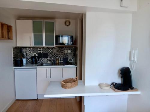 une cuisine avec des placards blancs et un comptoir blanc dans l'établissement Cosy Space rue des Cloutiers, à La Rochelle