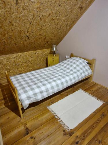 a small bed with a checkered blanket on a wooden floor at Żwirowa Góra - Domki nad Narwią in Tykocin