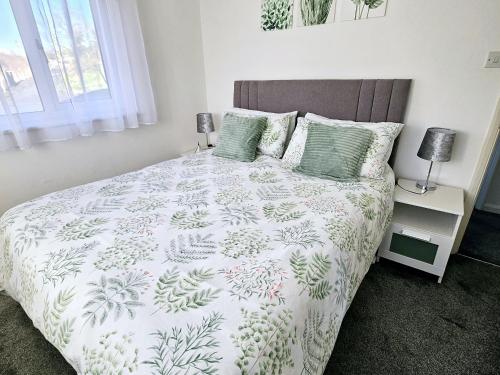 a bedroom with a bed with a green and white comforter at Modern 2 bedroom apartment in Historical Spa town in Droitwich