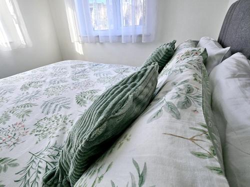 a bed with a green and white comforter and pillows at Modern 2 bedroom apartment in Historical Spa town in Droitwich